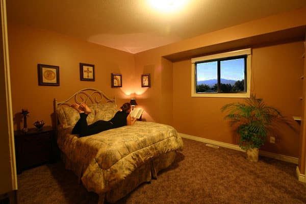 A person relaxing on bed in nice bedroom with a Kelowna view while in rehab.