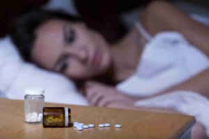 woman considers her prescription addictions as she lays on her bed